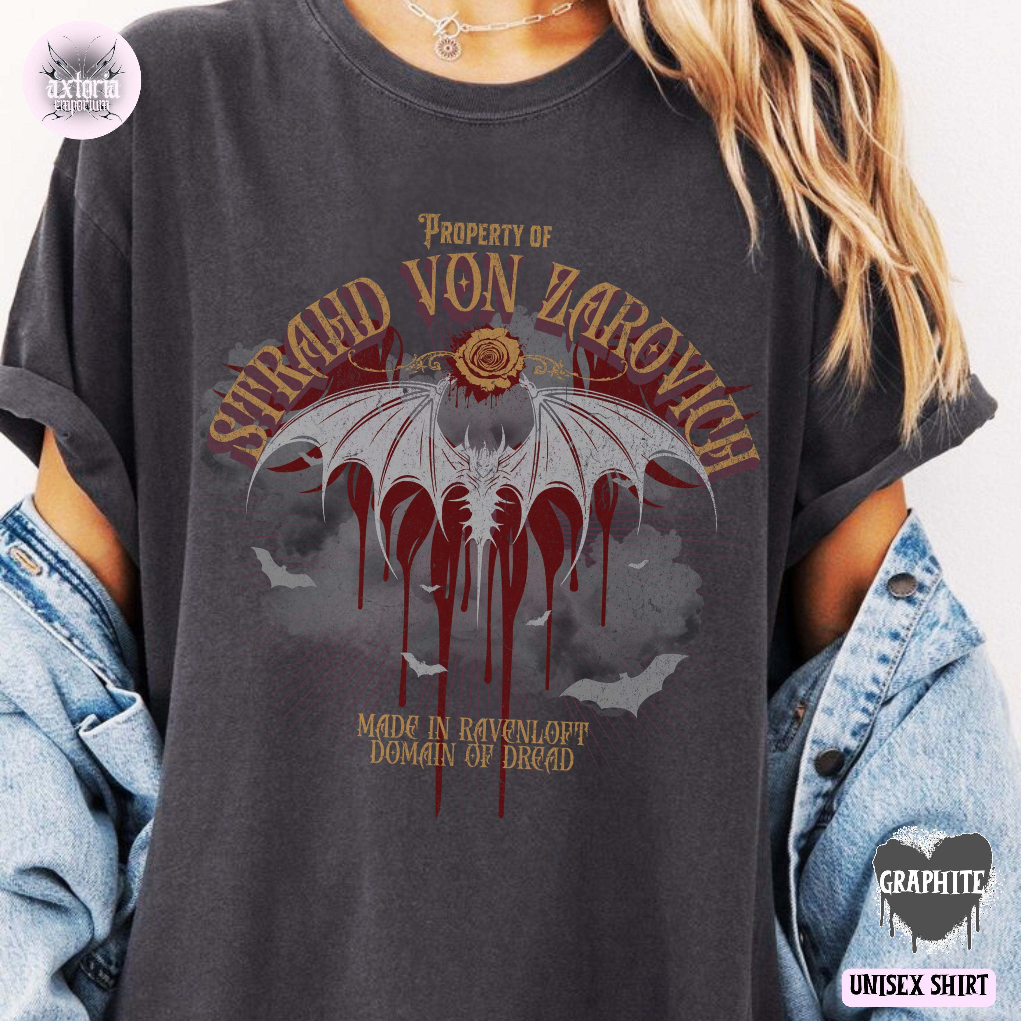 Person wearing a Dungeons and Dragons dark gray t-shirt with a bat and rose design and text, reading "Property of Strahd von Zarovich, Made in Ravenloft Domain of Dread"
